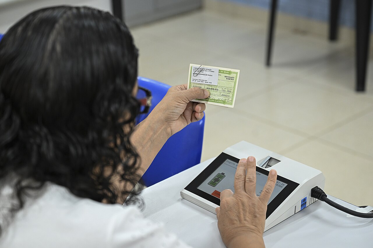 A voter holds her voter card at a biometric reader at a polling station in Brazil.