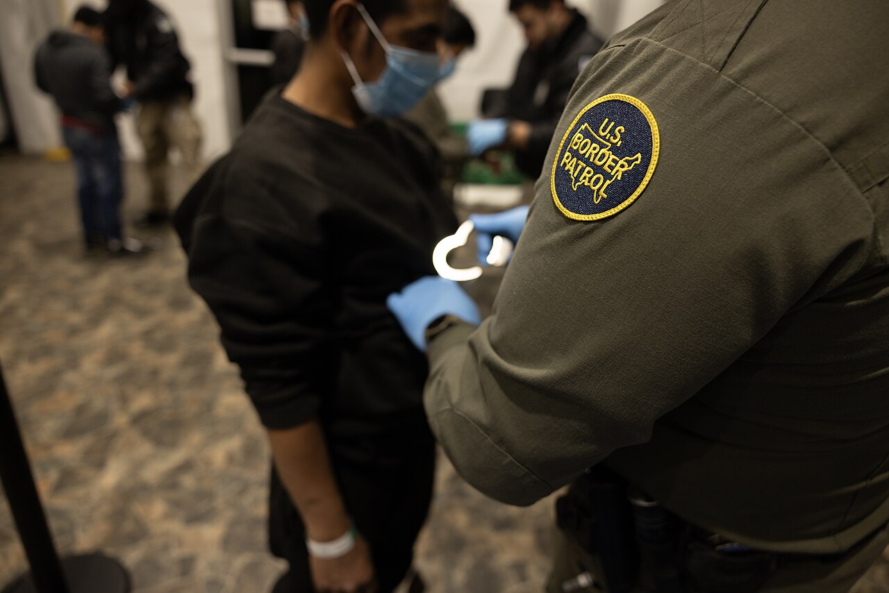 A U.S. Border Patrol agent processing a man in custody.