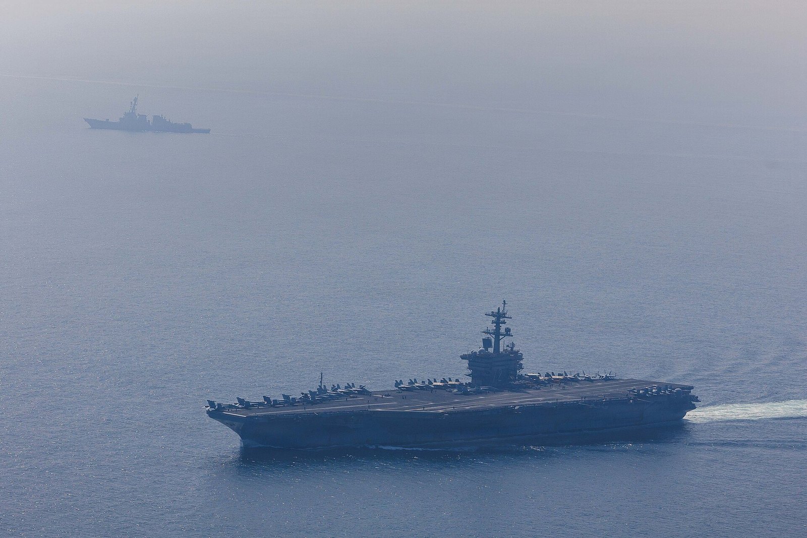 The aircraft carrier USS Abraham Lincoln and the destroyer USS Frank E. Petersen Jr. sail in the Arabian Sea.