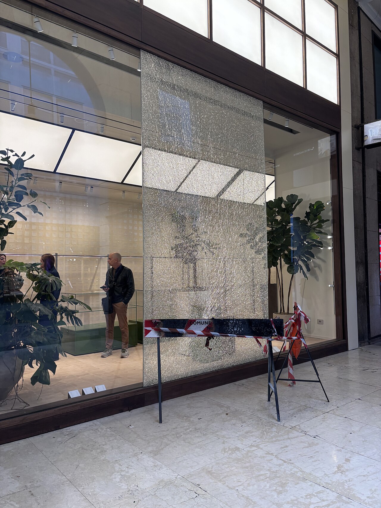 A smashed shopfront window in Milan, taped off after the unrest.