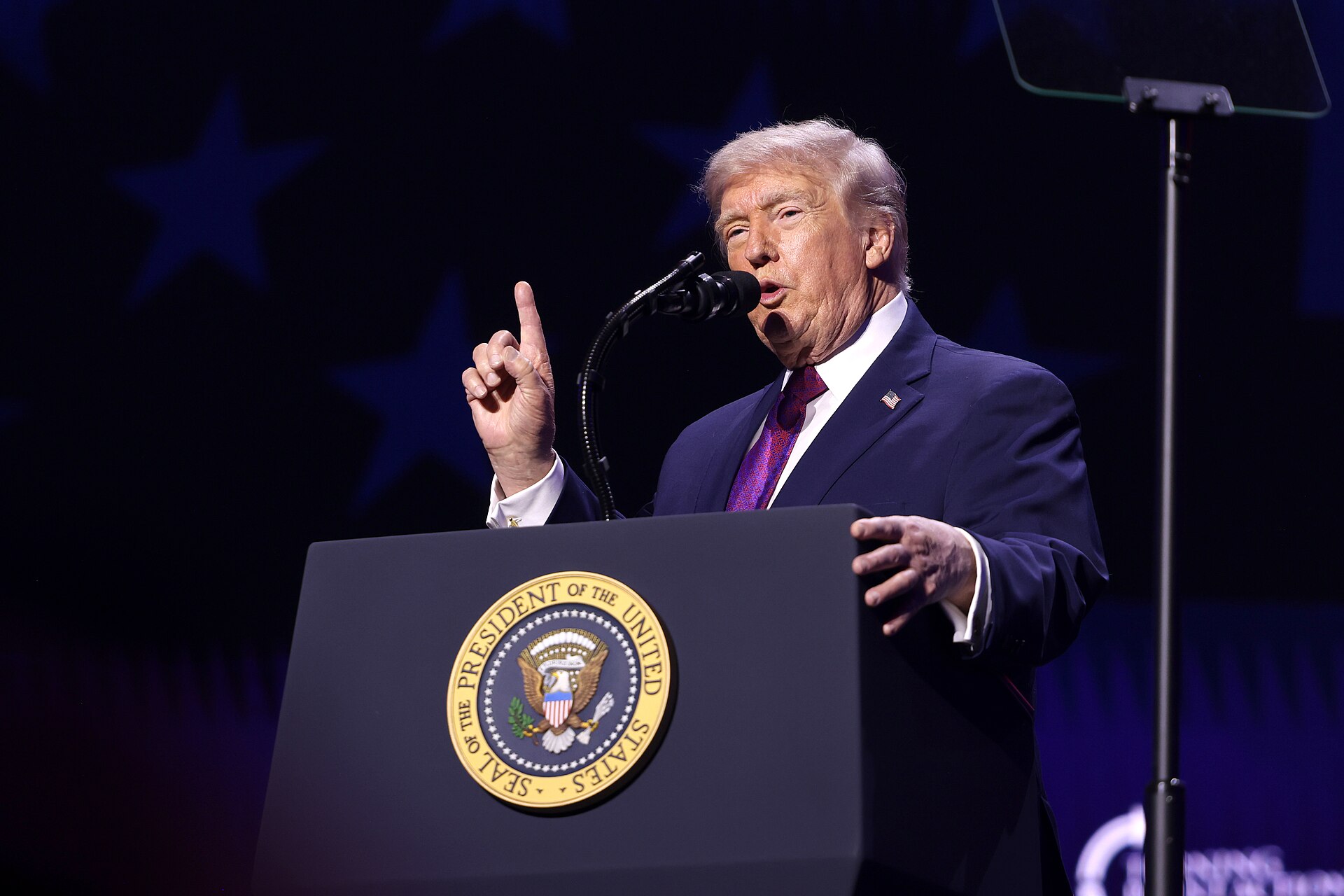 President Donald Trump speaking at a rally podium.